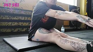 an alternative girl with tattoos stretches her young body during a sexy session at the gym
