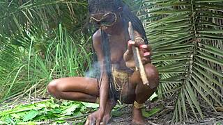 hot african native woman cooks in jungle kitchen with nature around her skinny frame