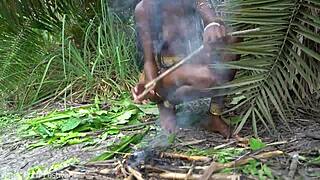 hot african native woman cooks in jungle kitchen with nature around her skinny frame